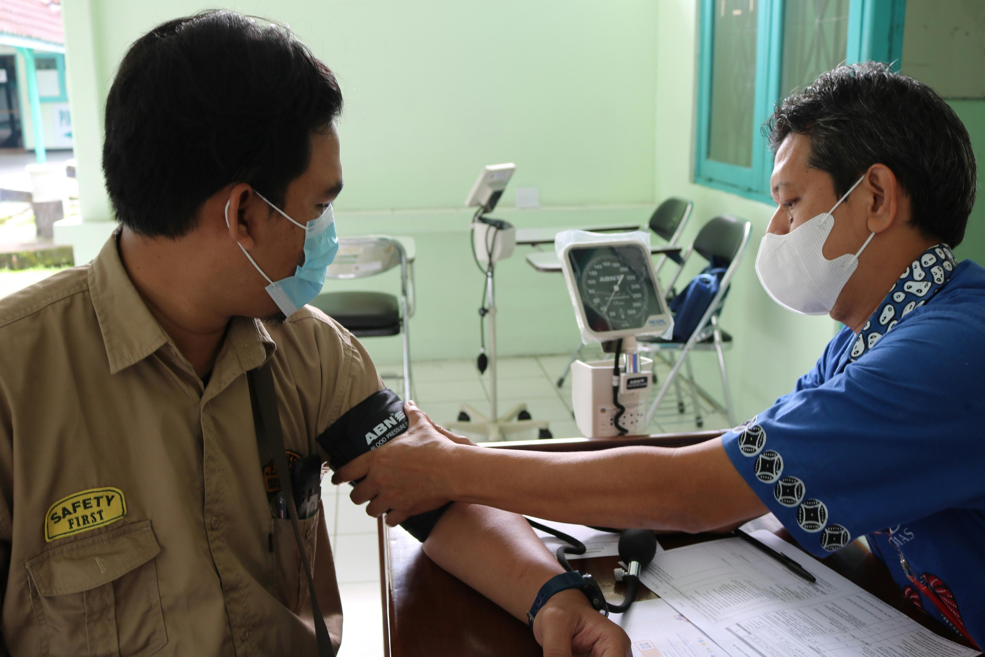 Doctor examining corporate employee during medical camp blood pressure check at office in India